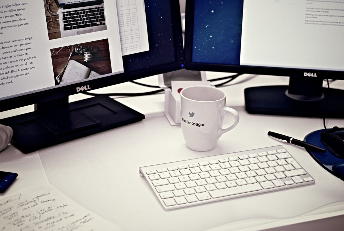 Un bureau avec deux écrans et une tasse de café